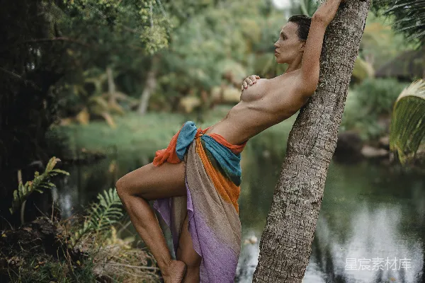 一个穿着连衣裙的人靠在一棵树旁河边