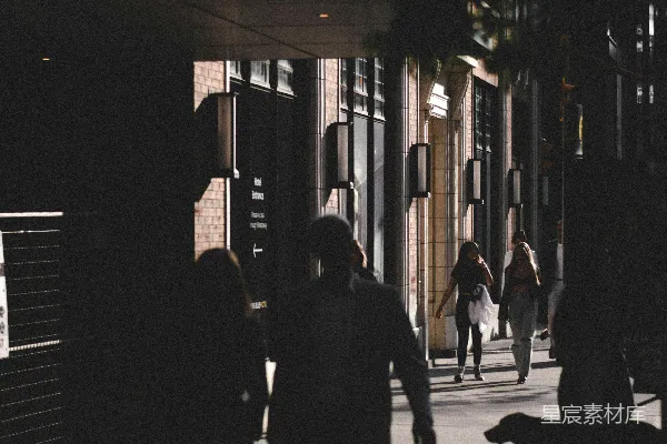高清摄影 一群人沿着一排高楼大厦旁的街道行走。
