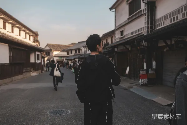 高清摄影 一个男人正走在一排高楼旁边的路上。