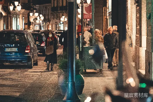 高清摄影 夜晚的城市街道，人们在人行道上行走。