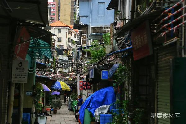 高清摄影 一条狭窄的城市街道，两旁是建筑物和雨伞。