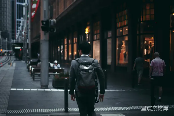 高清摄影 一个穿黑色夹克的男人在夜间走在人行道上。