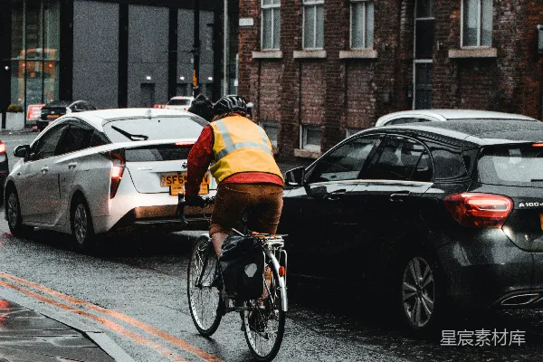 高清摄影 一个骑自行车的人在雨中沿着街道骑行。
