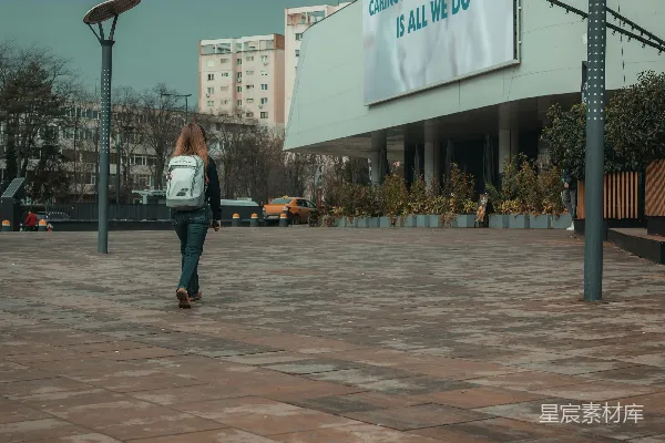 女人走过一栋有大型广告牌的建筑前。