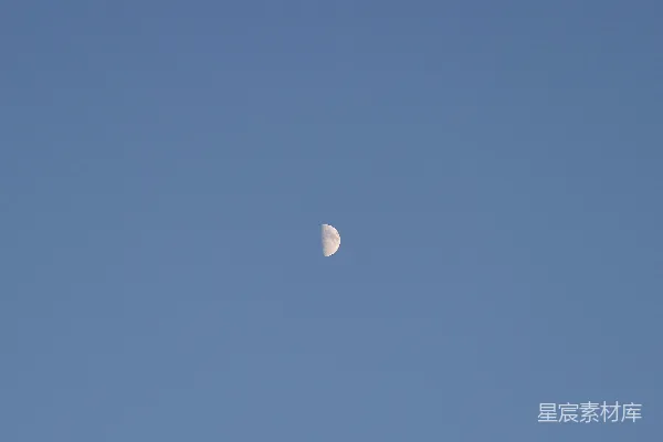 半个月亮出现在晴朗的蔚蓝天空中