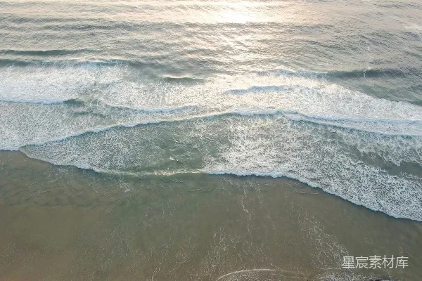 海滩上空俯视的景象，海浪涌来