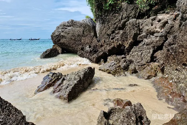 一块有岩石的沙滩上有一条船在水上