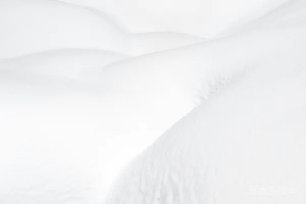 高清摄影 一张被白雪覆盖的床，上面铺着白色的床单和枕头。