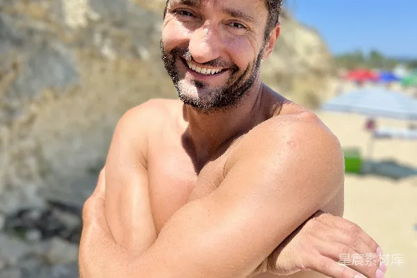 一个男人在晴朗的海滩上微笑。