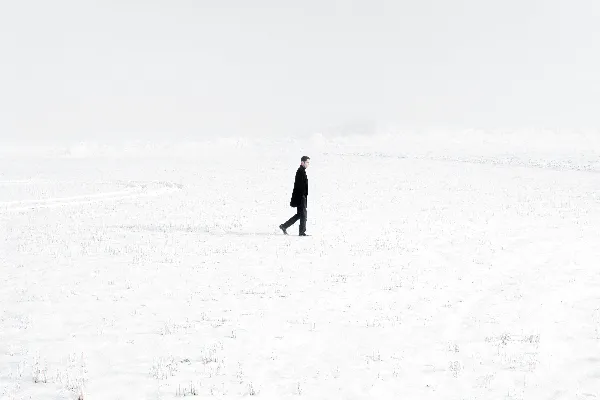 高清摄影 穿着黑色外套的人在白天的积雪覆盖的田野上行走。