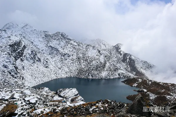 覆盖着白雪的山峦，湖水周围环绕着岩石。