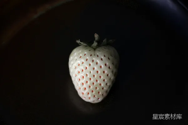 高清摄影 一个白色的草莓放在一个黑色的盘子上面。