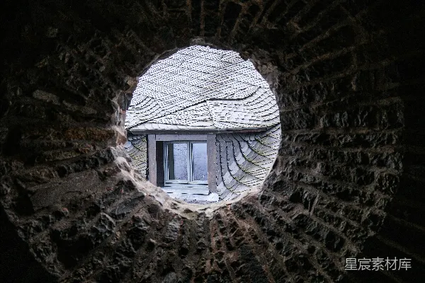 透过圆形石窗看到一座建筑