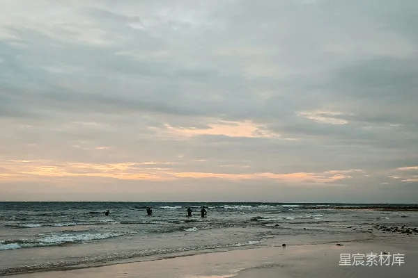 一群人在海滩上站立，旁边是海洋。