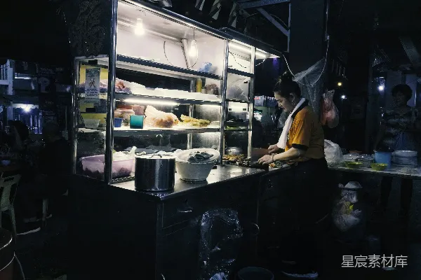 夜市摊位上的售卖者准备食物。