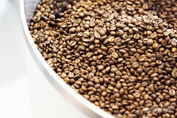容器中盛着用勺子舀出的 roasted 咖啡豆。