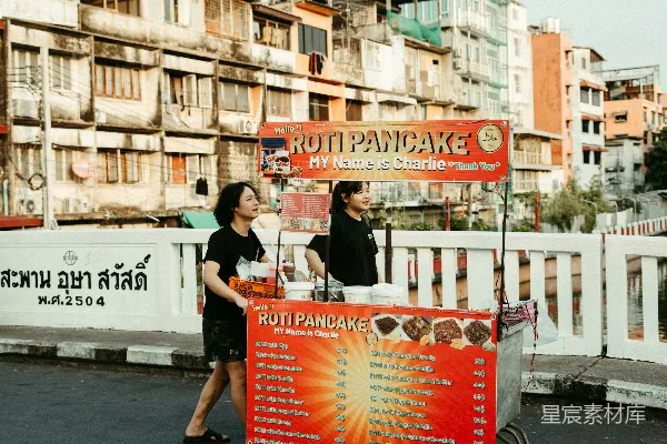 两名人员操作一家流动的.roti pancake快餐车。
