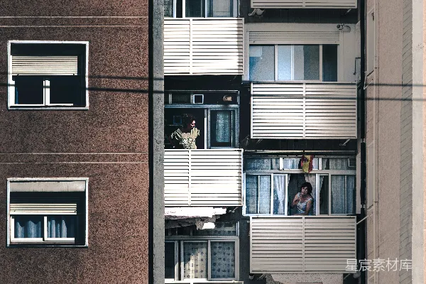 黑色夹克的男人站在棕色砖砌建筑旁