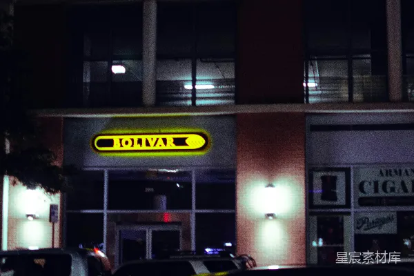 夜晚建筑物的外观，前有汽车停放。
