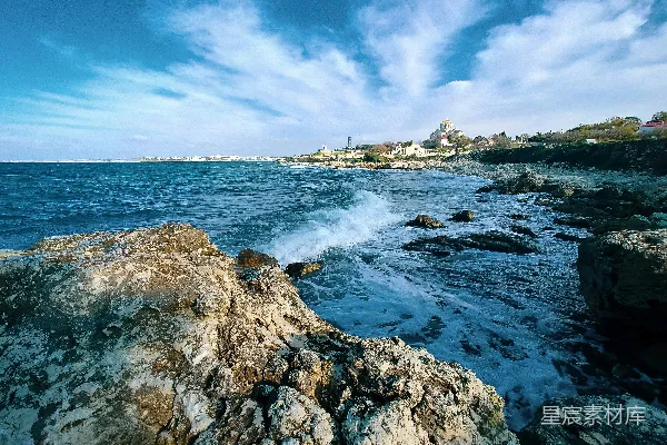 高清摄影 白天，蓝色和白色云朵下的岩石海岸上，海浪拍打着岩石。