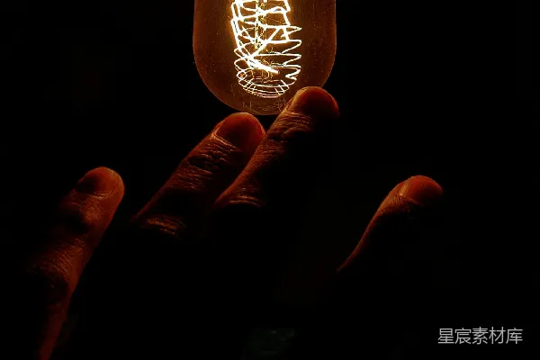 高清摄影 一只手在黑暗中握着一个灯泡。