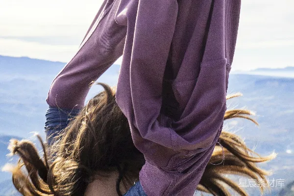 长发女子身穿紫色卫衣在户外