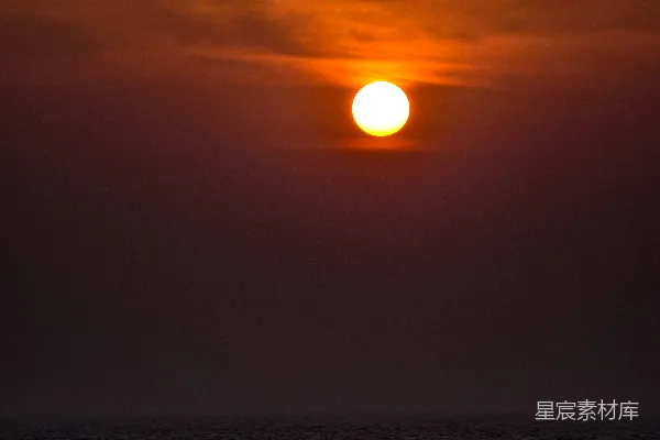 阴天里太阳正沉落在海面上。