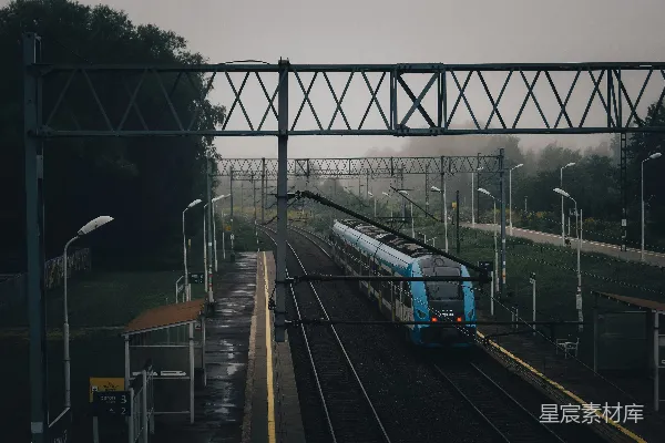高清摄影 一辆蓝色的火车沿着森林旁边的道路轨道行驶。