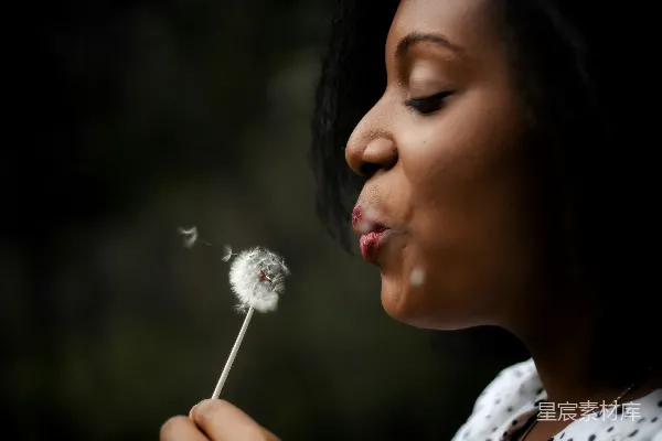 高清摄影 穿着白色上衣的女人吹着蒲公英种子
