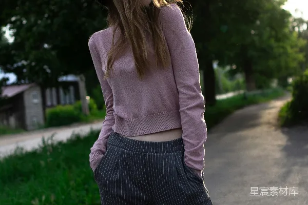 戴帽的女人穿着粉红色毛衣在小径上行走