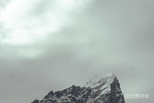 雪冠山峰下的阴云密布天空