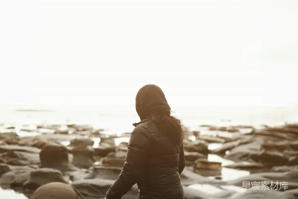 女人走在黑色和棕色的岩石上