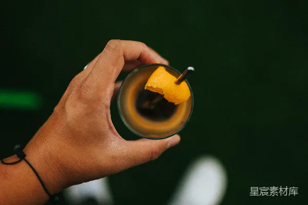 手持黑色陶瓷杯的人手中拿着一杯黄色液体
