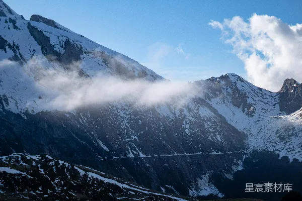 覆盖着白雪和云雾的高山在蔚蓝的天空下