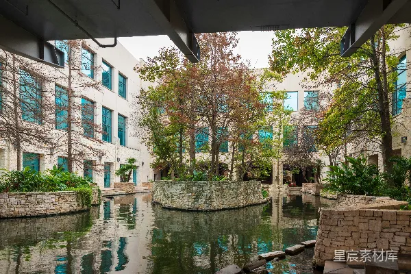 一条河流穿过一片繁茂的绿色公园，旁边是高大的建筑物。