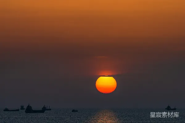 高清摄影 海面上夕阳西下，船在水中漂浮。