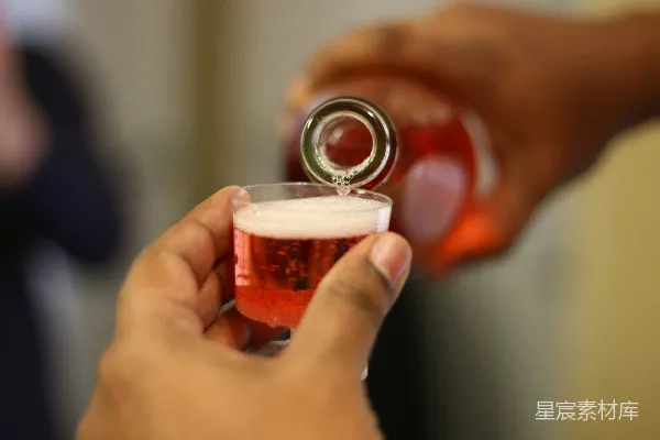 手持透明酒杯的人举着一杯棕色液体