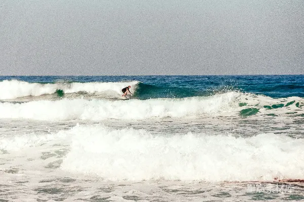 一个骑手坐在冲浪板上 surfing atop a wave