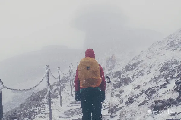 橙色夹克的男人在覆有积雪的地面上白天站立