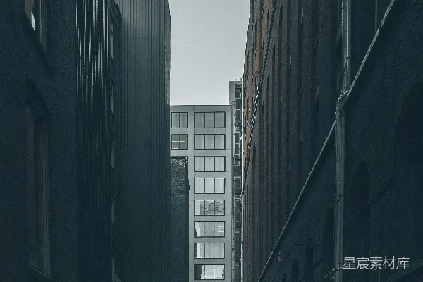高清摄影 一个男人在城市建筑物中间行走，天空中布满阴沉的云层。