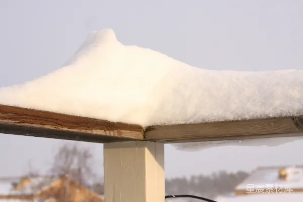 覆盖着白雪的屋顶上有一只鸟栖息。