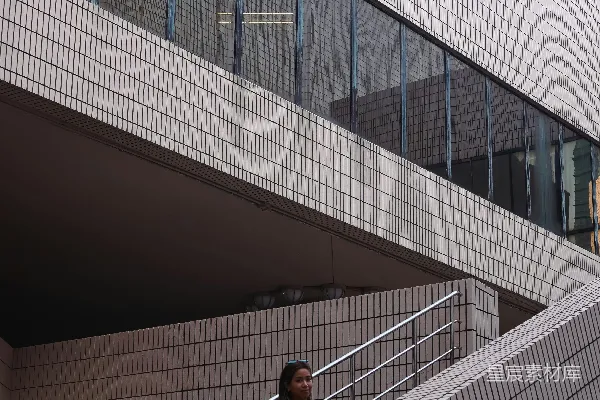 红衣女子站在现代楼梯上。
