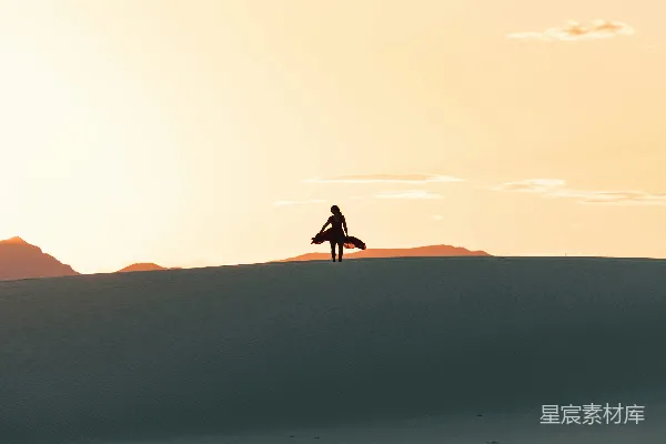 白天沙漠中人的 silhouette 走路的轮廓