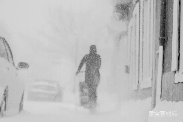 一个男子走在覆盖着积雪的街道上