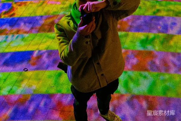 一个穿着外套的人站在彩色的地面上