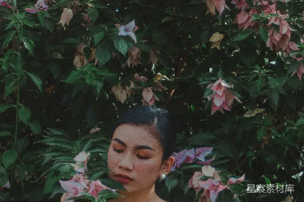 一个女人站在一棵开着粉花的树前