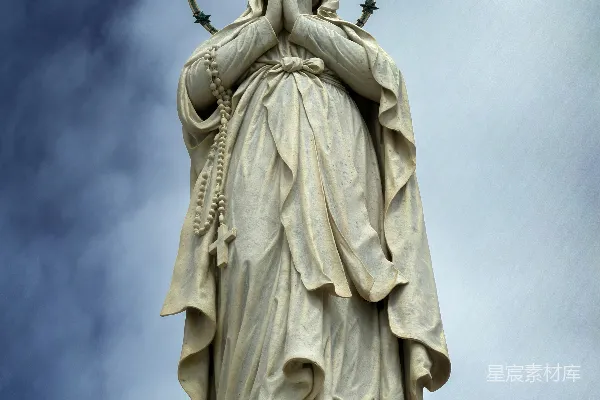 一位手持祈祷姿势的女性雕像，头上带有光环。
