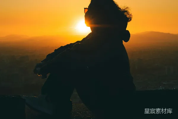 一个坐在台阶边缘的人望着夕阳西下。