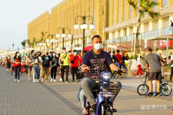 白上衣红条纹短袖的男人在白天骑摩托车。