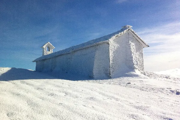 一座小的白色建筑坐落在一片覆雪的斜坡上。
